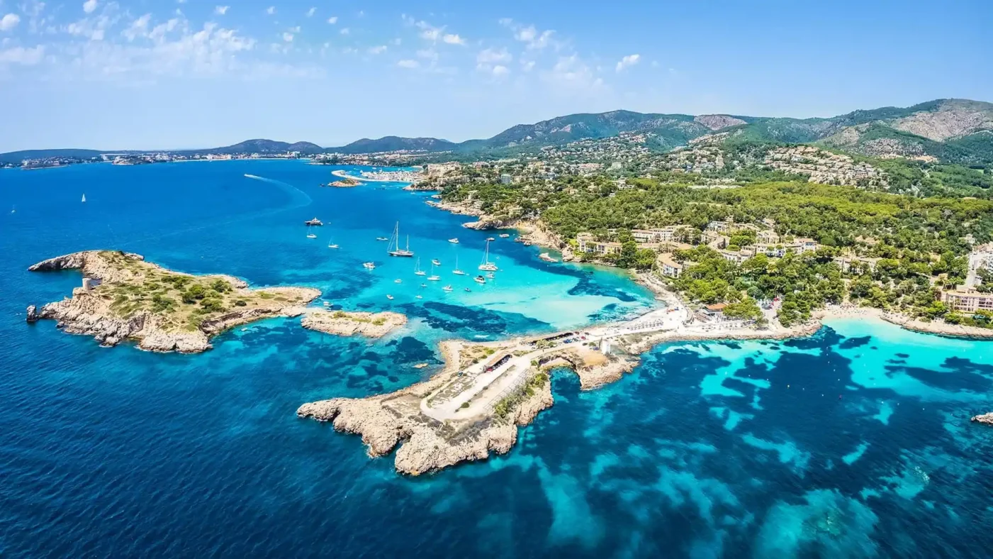beach with blue crystal clear waters and sunny day. Some boats around.