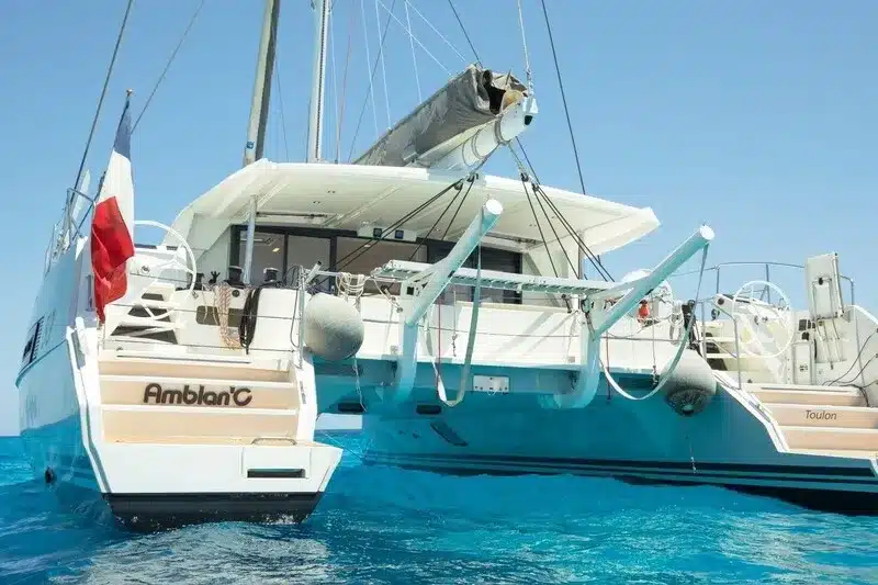 catamaran in charter in mallorca anchored at a bay with blue water.