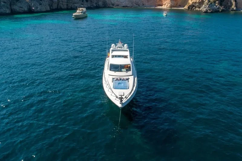 Yacht zur Miete auf Mallorca, vor Anker an einem Strand. Sonniger Tag und grünliches Wasser.