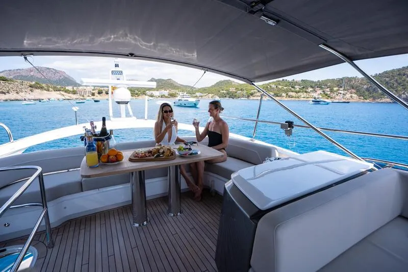 Flybridge in a Yacht. Sunny day. Spacious sofa area with a wood table. Teak floor.