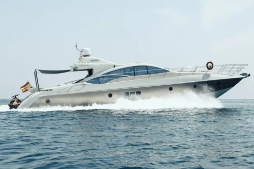 Boot mieten Mallorca. Yacht unterwegs auf türkisfarbenem Meer. Das Yacht ist weiß mit goldenen Akzenten. Geräumig und sehr groß. Ein Jet-Ski befindet sich auf der Badeplattform.